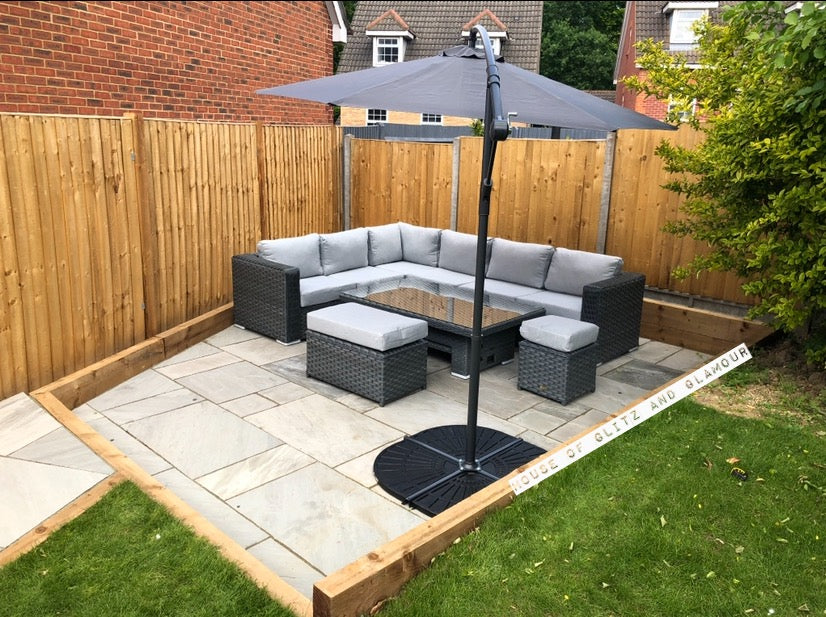 Monte Carlo Rattan Wide Corner Sofa Dining Set In Grey on a flagged part of the garden with Umbrella.
