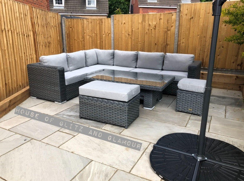Monte Carlo Rattan Wide Corner Sofa Dining Set In Grey with a wooden fence around the back.
