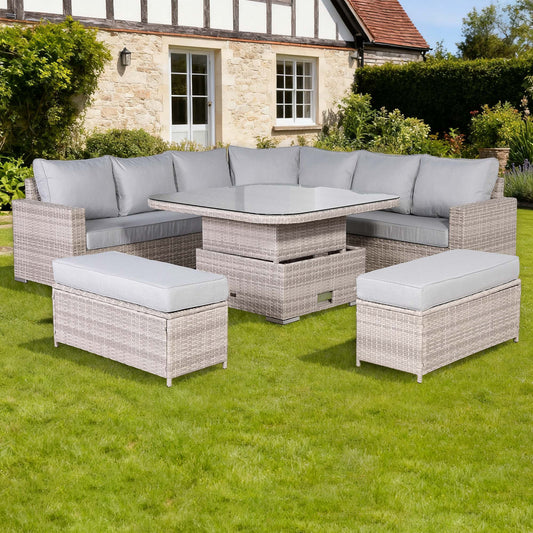 Garden furniture set with sofa, table, and ottomans on grass in front of a house.
